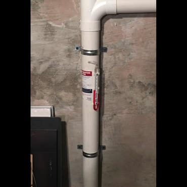 Vertical radon mitigation pipe installation inside a commercial facility by Green Earth Remediation.