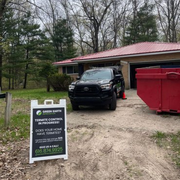 Green Earth Remediation vehicle and service sign at a homeowner's property advertising termite control services.
