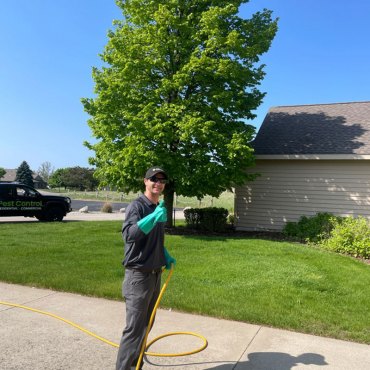 Green Earth Remediation technician applying eco-friendly pesticide to treat lawn pests at a residential property.