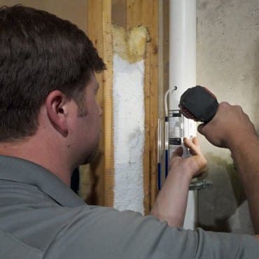 Green Earth Remediation technician ensuring tight sealing during radon mitigation system installation.