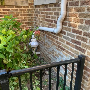 Radon mitigation piping installed by Green Earth Remediation, discreetly positioned near house plants.