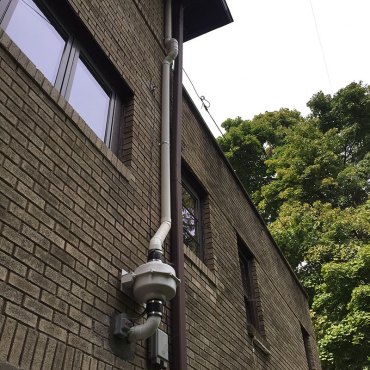 Efficient radon mitigation system installed on the exterior of a commercial building by Green Earth Remediation.