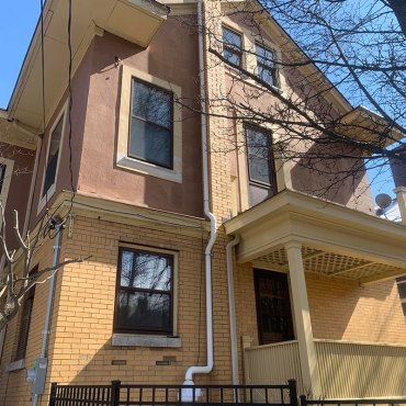 Exterior view of a residential building with Green Earth Remediation’s radon mitigation system installed.