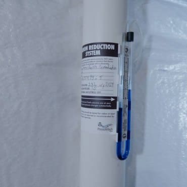 Certification tag on a radon mitigation system by Green Earth Remediation, ensuring compliance and efficacy.