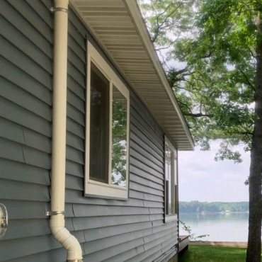 Radon mitigation pipe installed at a lakefront property by Green Earth Remediation, ensuring clean indoor air.