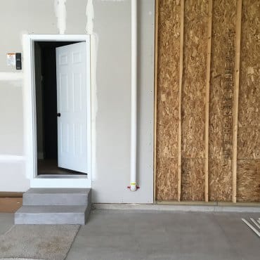 Radon vent pipe installation on the exterior of a residential building by Green Earth Remediation.