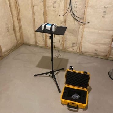 Radon detection equipment operating in a basement by Green Earth Remediation to ensure accurate radon level measurements.