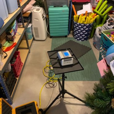 Setup of a radon testing device by Green Earth Remediation, connected to a laptop for real-time data analysis.