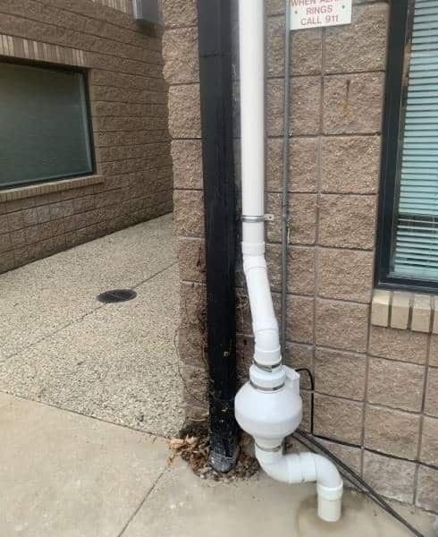 Commercial radon mitigation system on building exterior.
