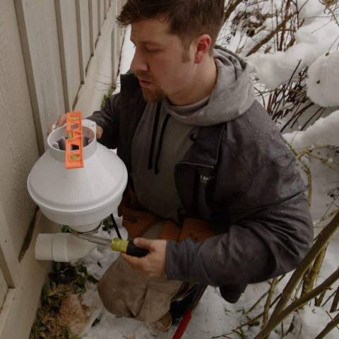 Technician from Green Earth Remediation installing residential radon mitigation system.